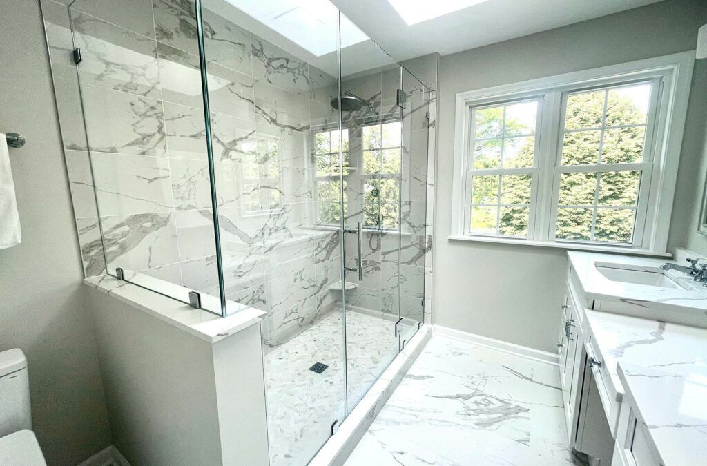 Large marble tiled shower with frameless glass and a skylight above