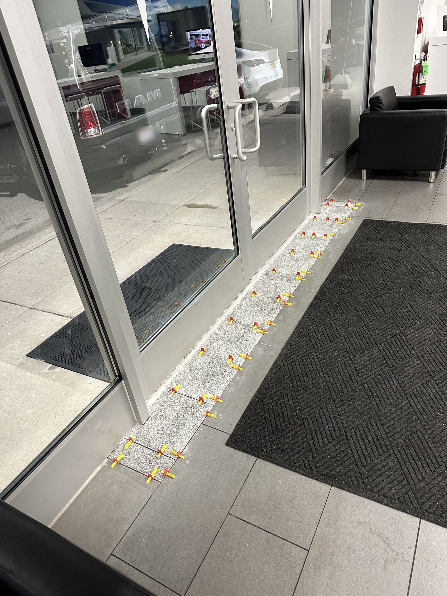 Large format floor tile being set with levelling clips at a commercial showroom entrance