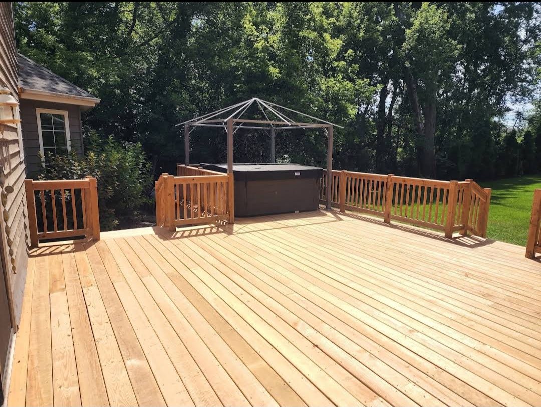 Large cedar deck with a hot tub and gazebo frame