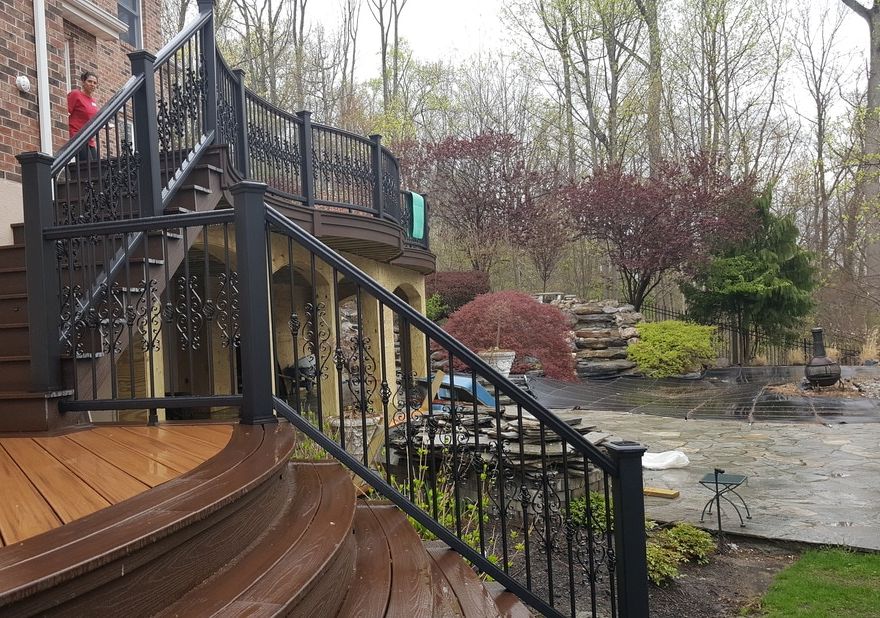Curved deck with decorative wrought iron balusters and stairs