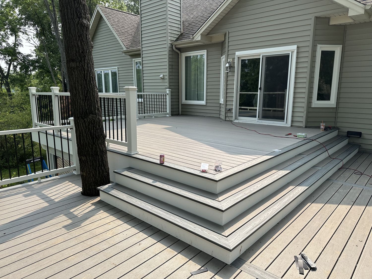 Grey composite deck with wide wraparound steps and black railings