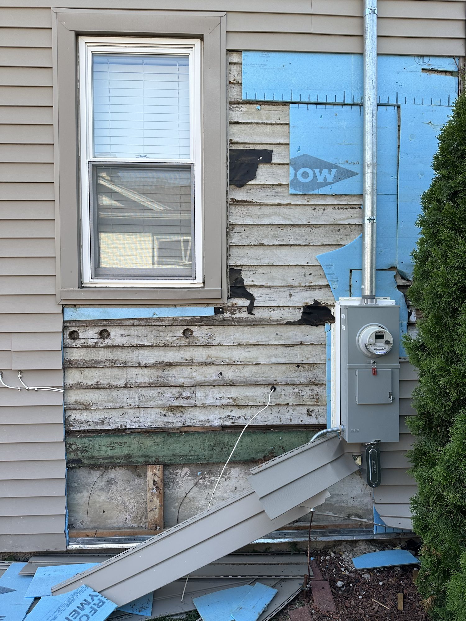 House siding removed exposing water damaged sheathing and framing